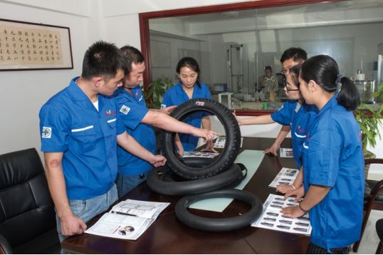 Operarios y experto en sala de inspección revisando las llantas para moto